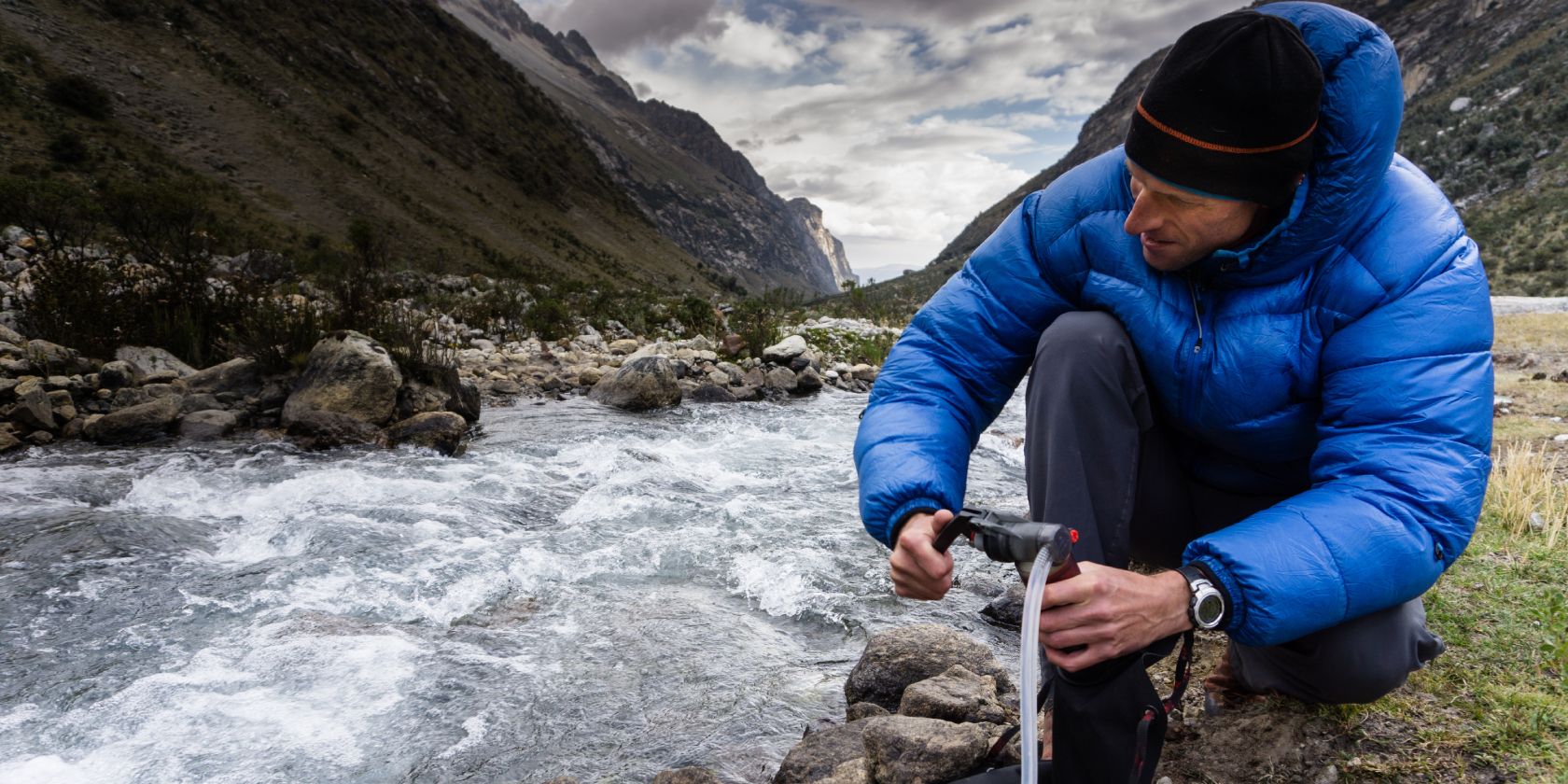 Backpacker using a water filter on a mountain stream