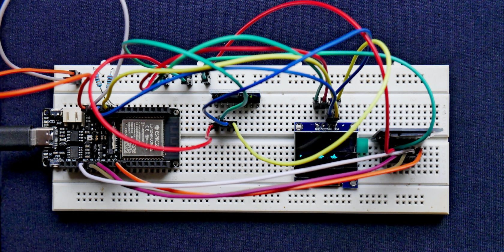 A DFRobot FireBeetle development board hooked up to an accelerometer sensor, OLED display and an SD card module on a breadboard.