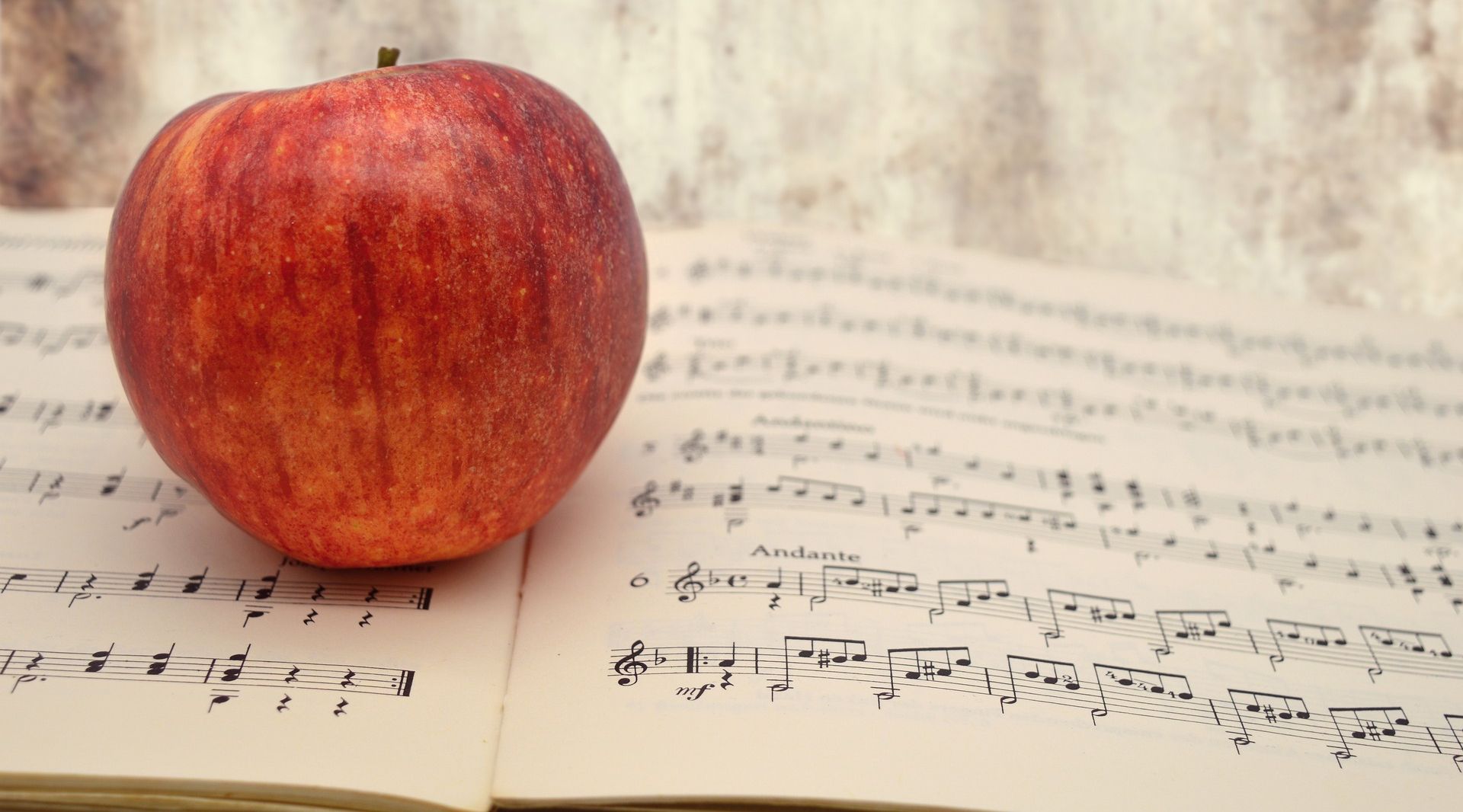 An apple sitting on top of classical music scoresheets. 