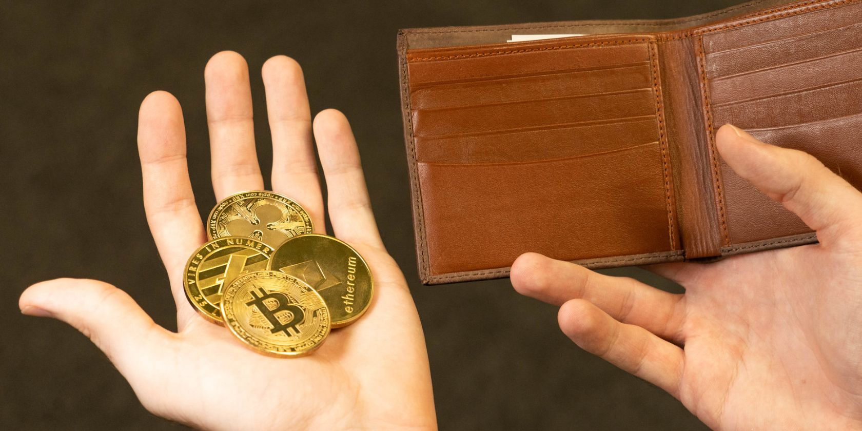 various crypto coins in hand next to leather wallet