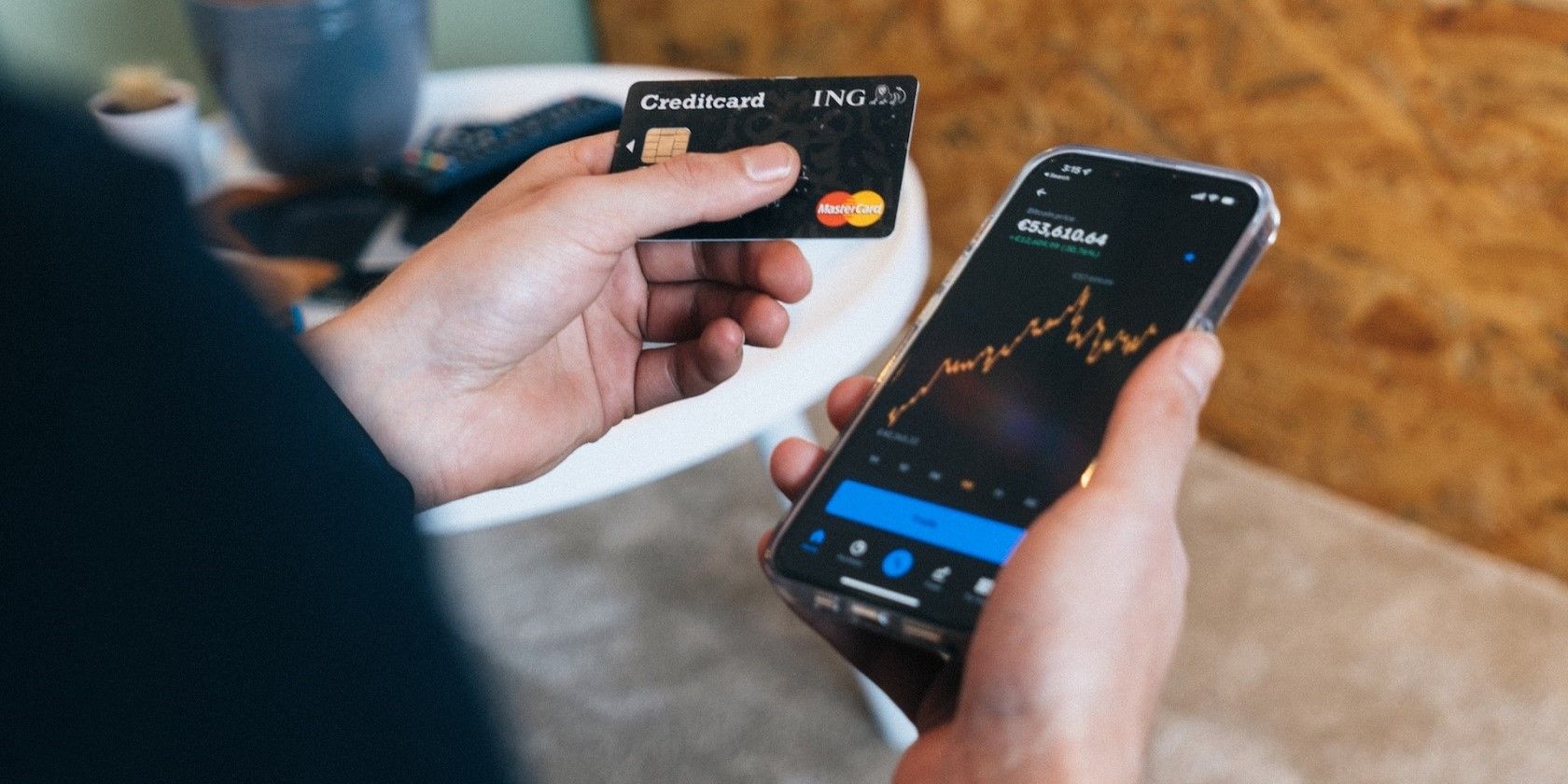A person holding a credit card in one hand and a mobile phone showing a crypto asset in the other hand