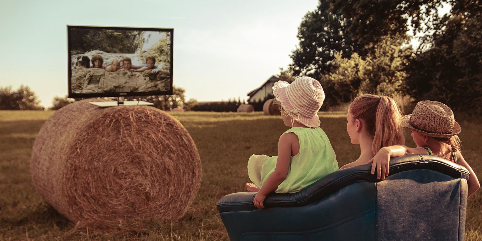 Một nhóm trẻ em trên cánh đồng đang xem TV ngồi trên một đống cỏ khô