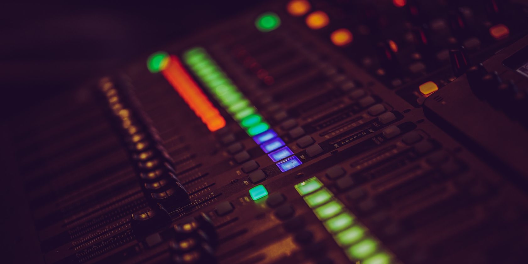 Faders in a mixing board with colorful lights