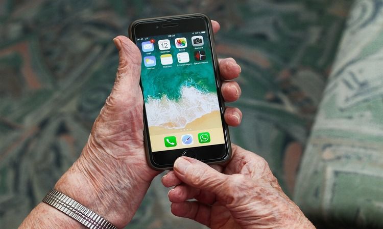 senior yang lebih tua memegang smartphone yang tidak terkunci di homescreen