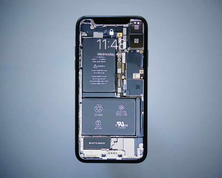 Layar iPhone menampilkan waktu dan gambar komponen internal ponsel