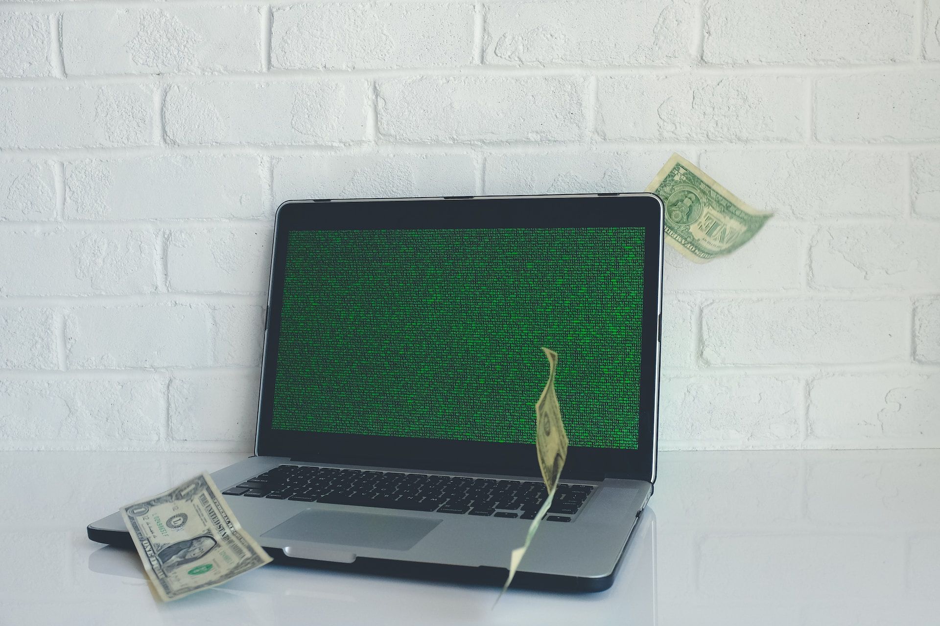 macbook với màn hình màu xanh lá cây và đô la xung quanh nó 