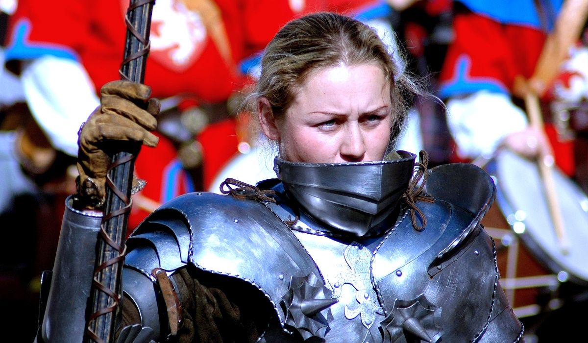 A woman in armor holds a weapon