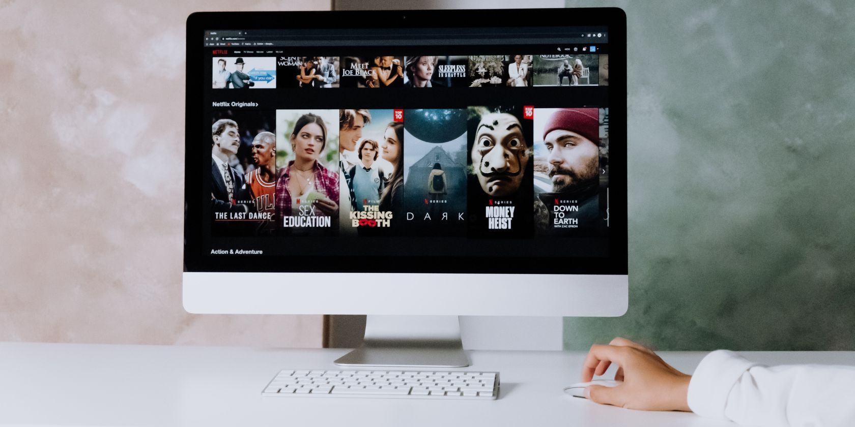 A person sitting at the desk with Netflix on an iMac screen