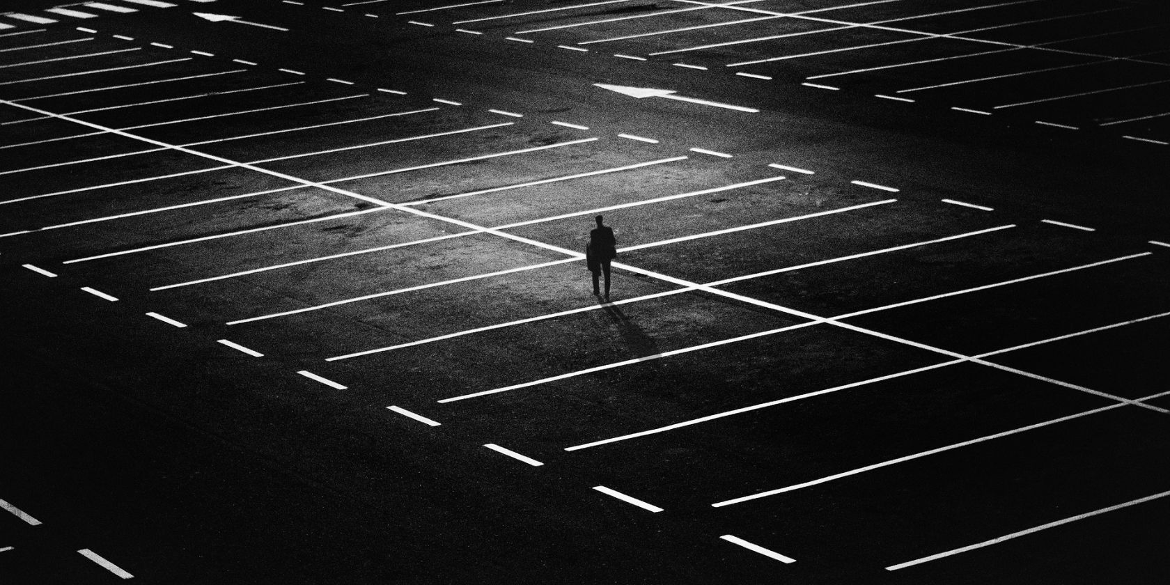 một người đàn ông đi bộ một mình trong một bãi đậu xe