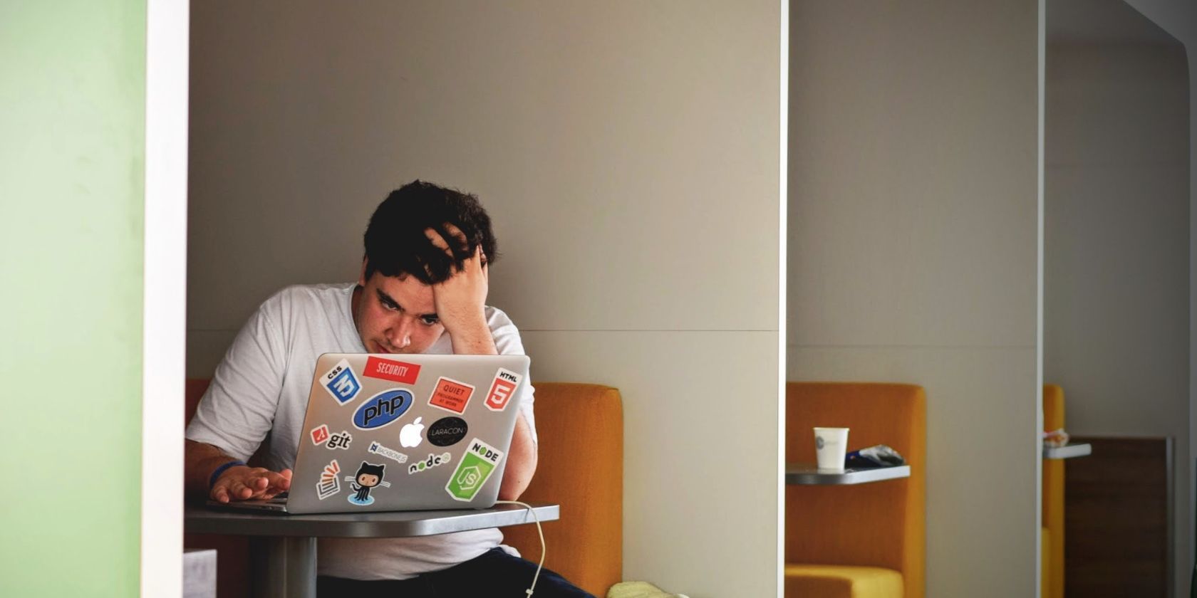 Một người đàn ông ngồi khó chịu khi nhìn vào MacBook