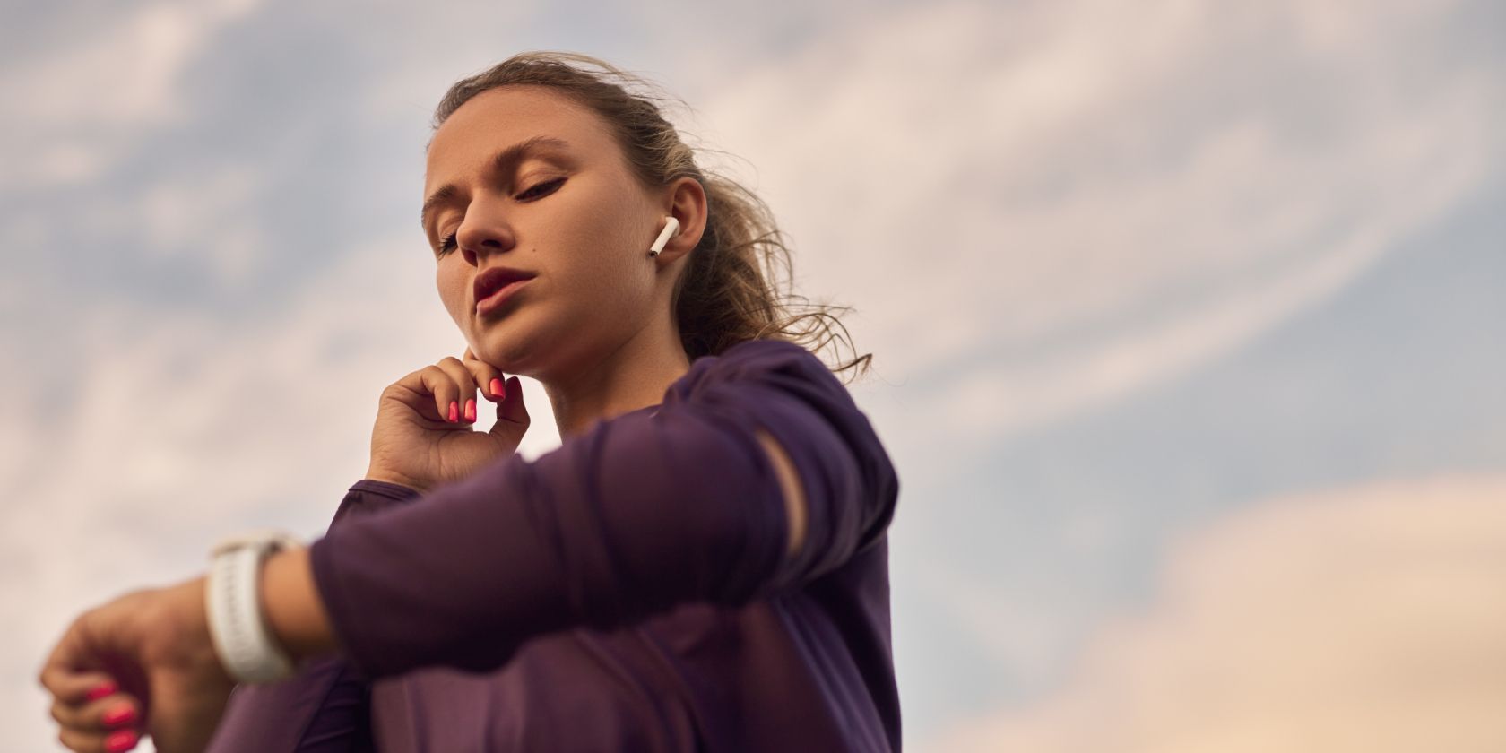 Person wearing active wear and using true wireless earbuds