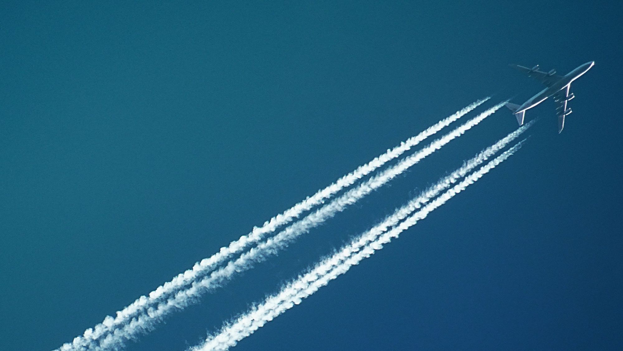 photo of plane in sky with contrails