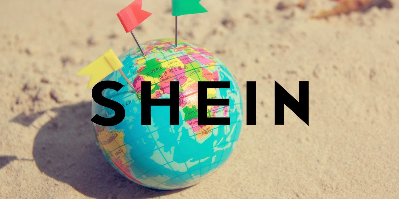 shein logo in front of small globe on sand