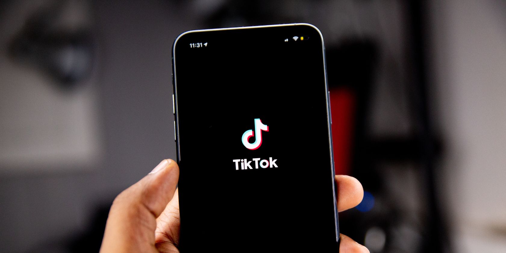 A hand holding a black phone with the TikTok logo on the screen