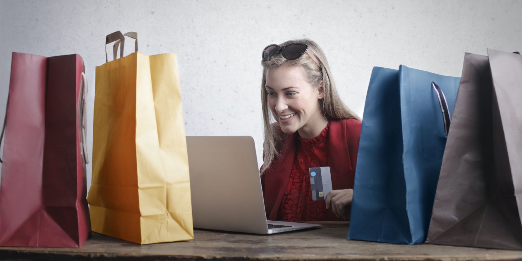Woman shopping on her laptop, with shopping bags next to her