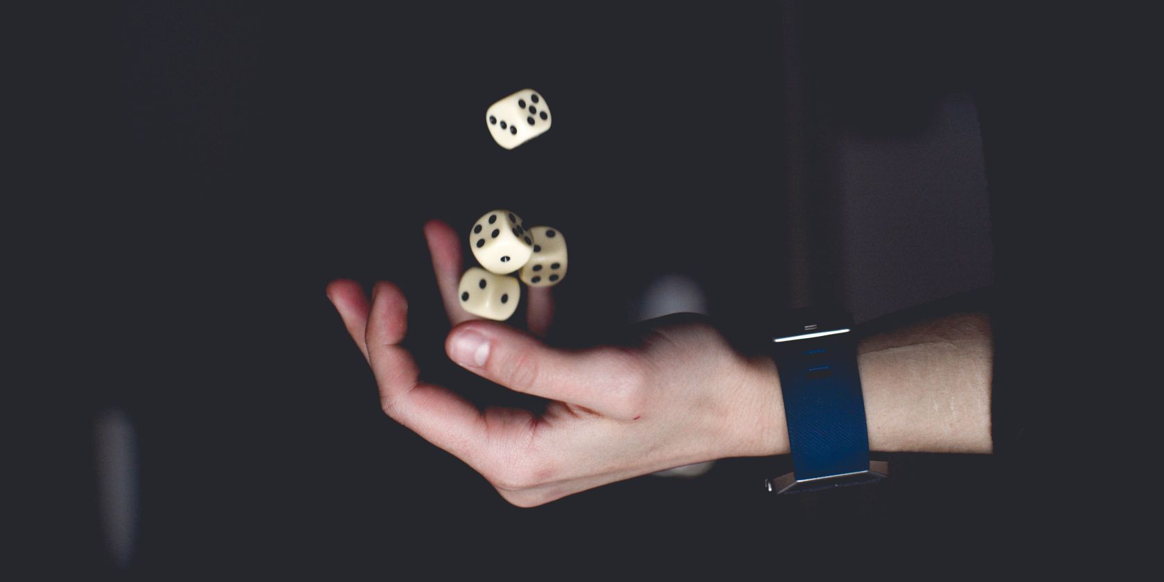 A hand catching four falling dice