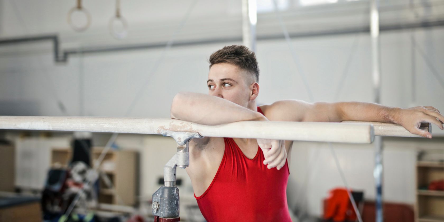 A man in red vest exercising on parallel bars at gym