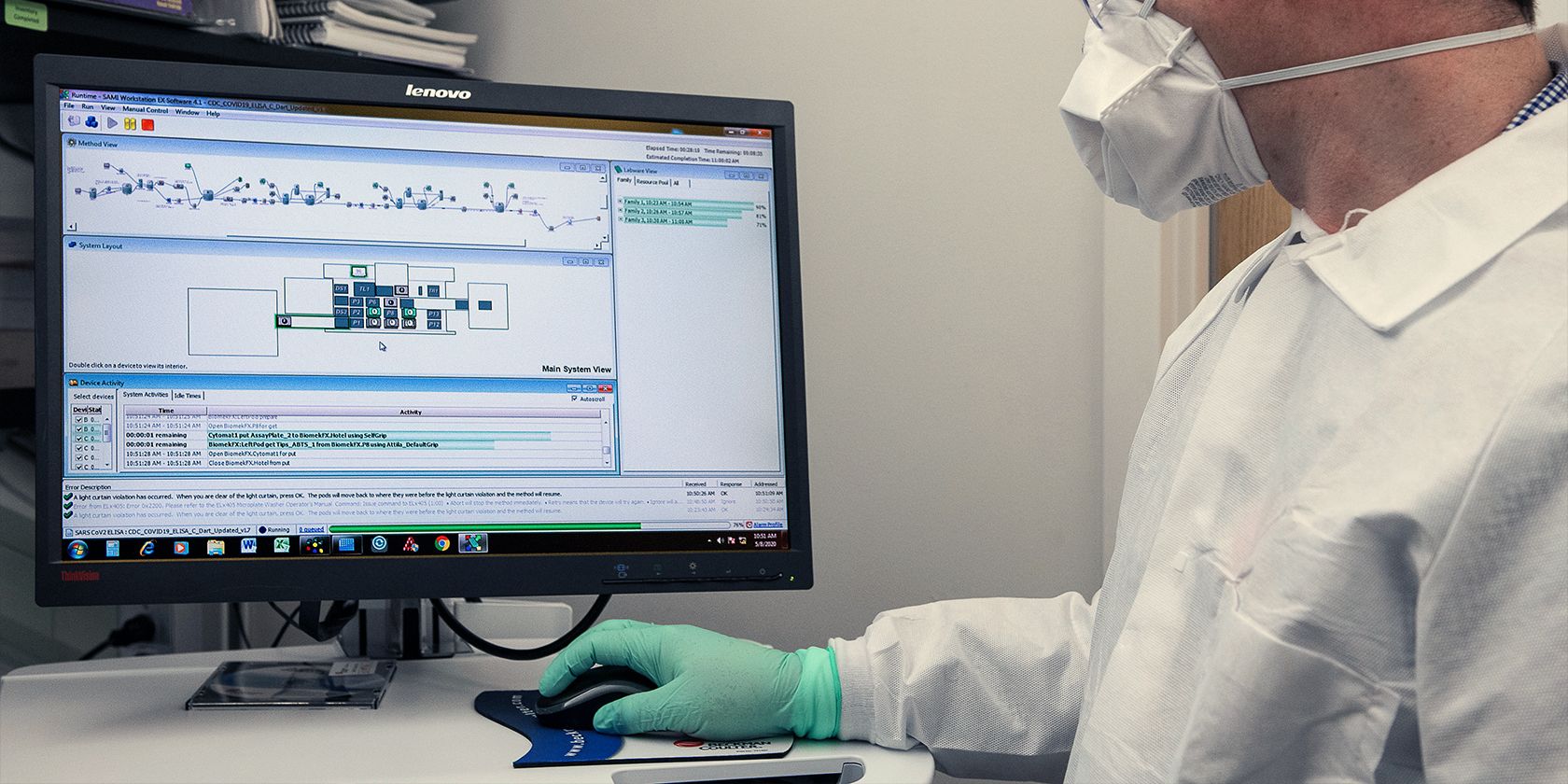 a person wearing a white coat and gloves and using a computer