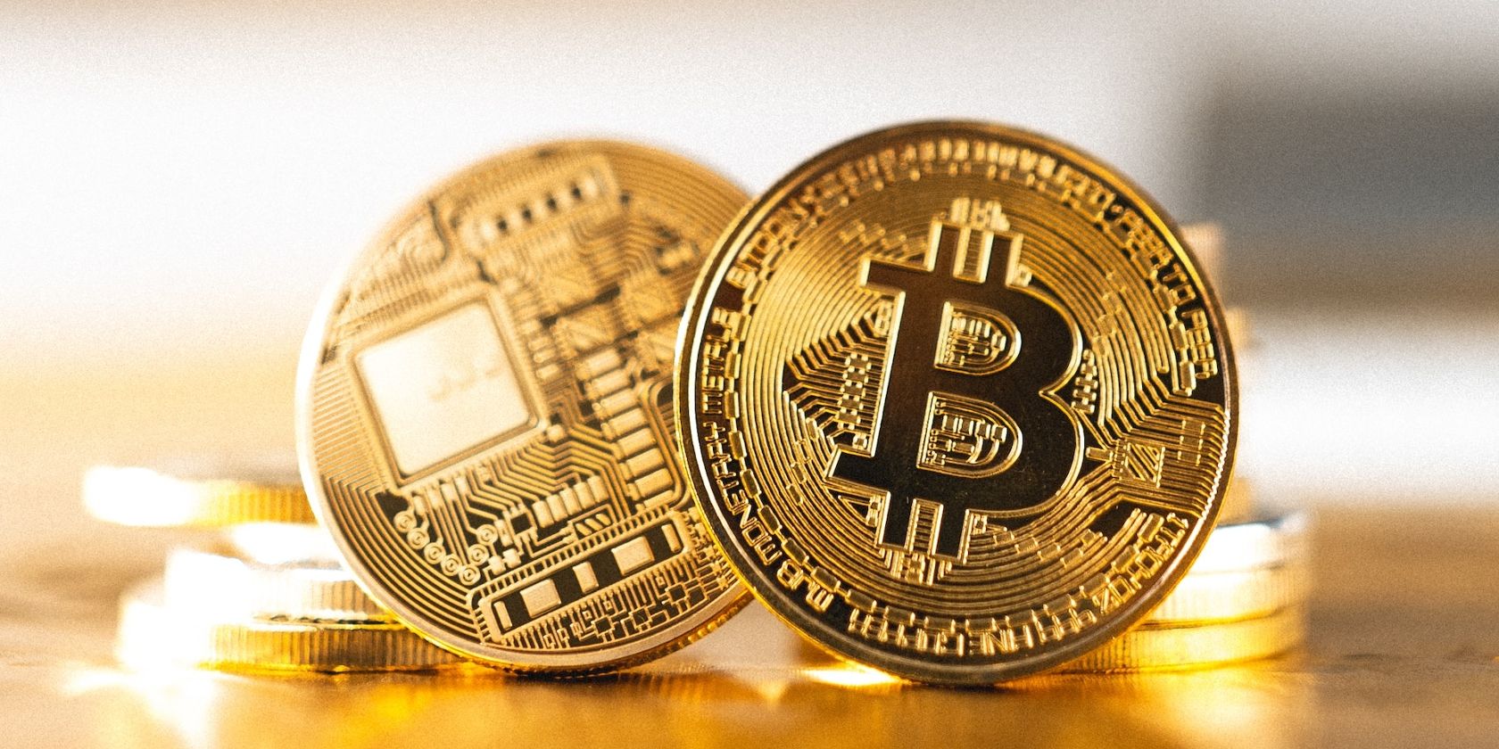 Two coins, one with the Bitcoin logo, placed upright beside other coins on a table