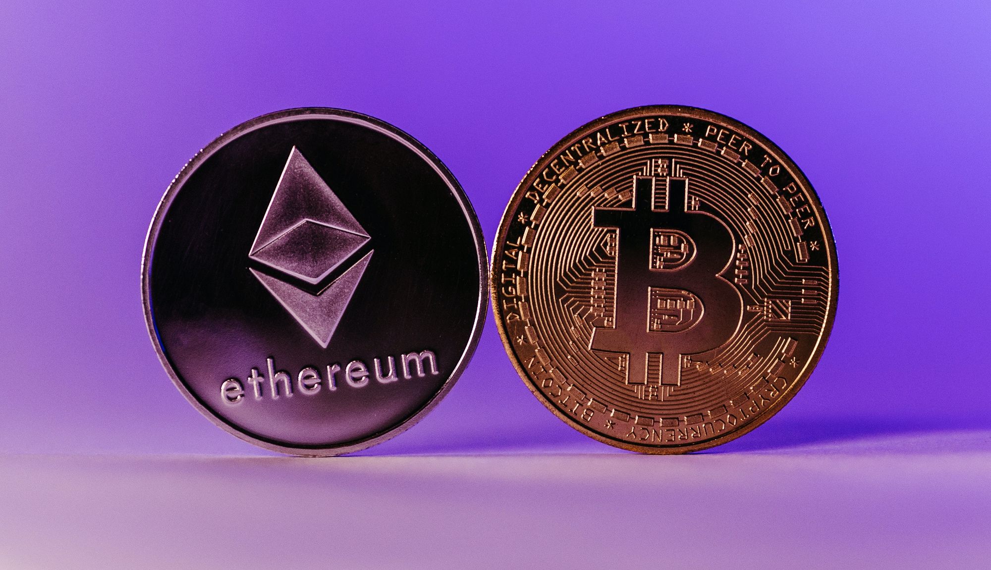 ethereum and bitcoin coins side by side on purple background