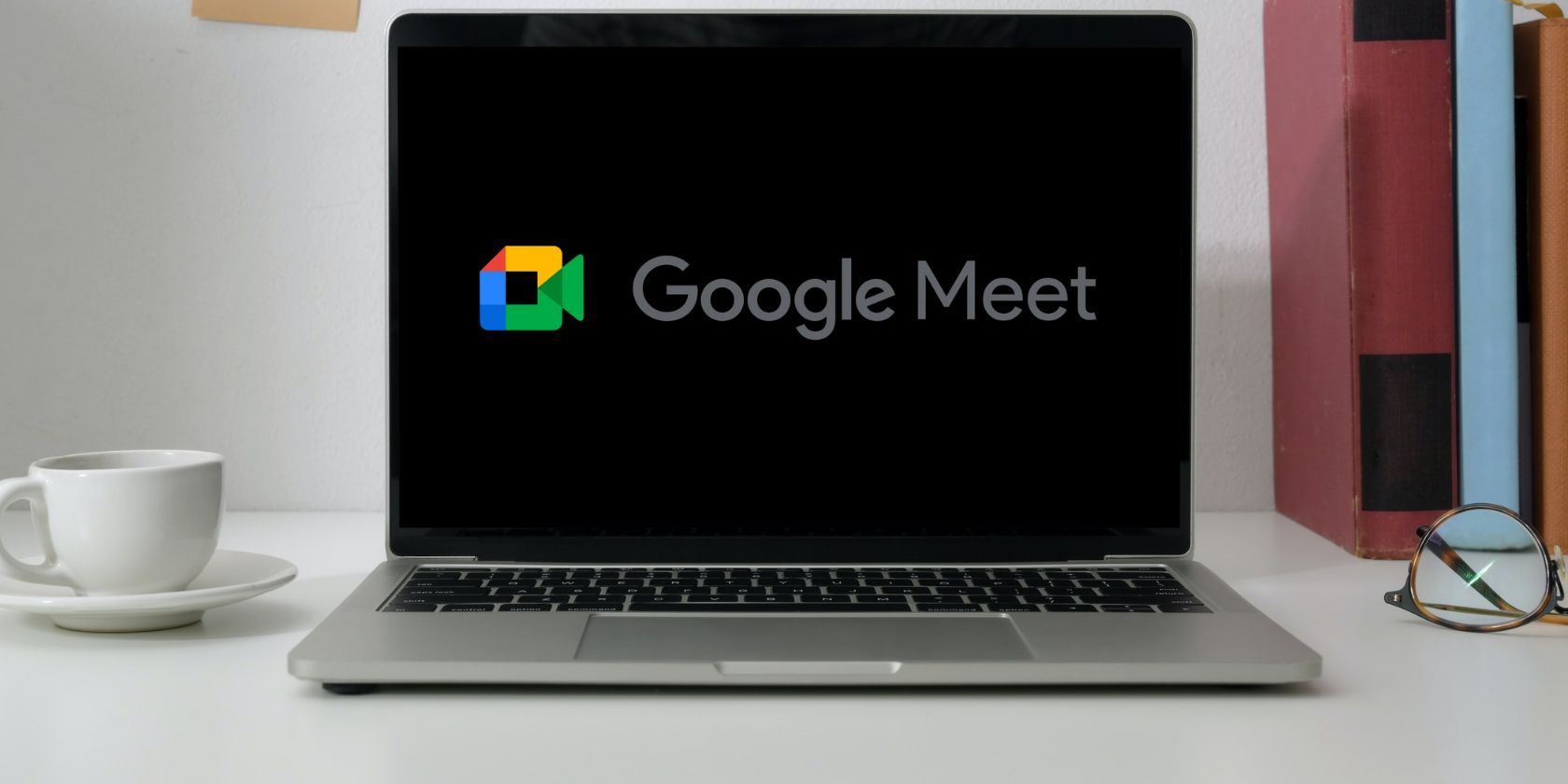 Google Meet logo on a laptop screen placed on a table. 