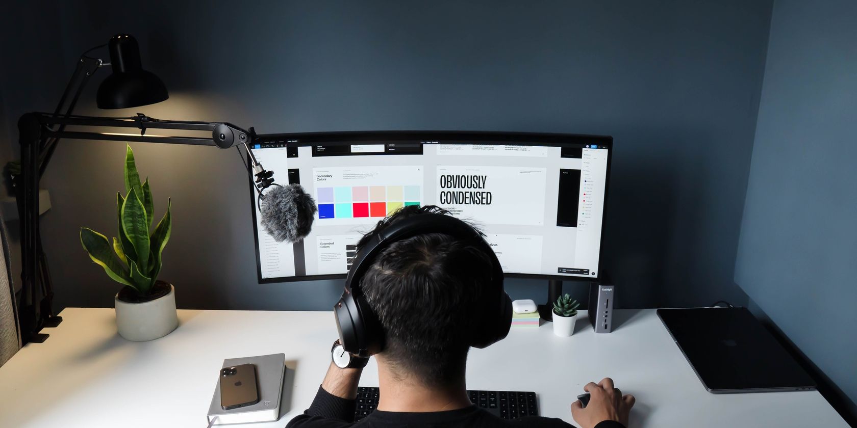 A graphic designer working at a desk with a pair on monitors.