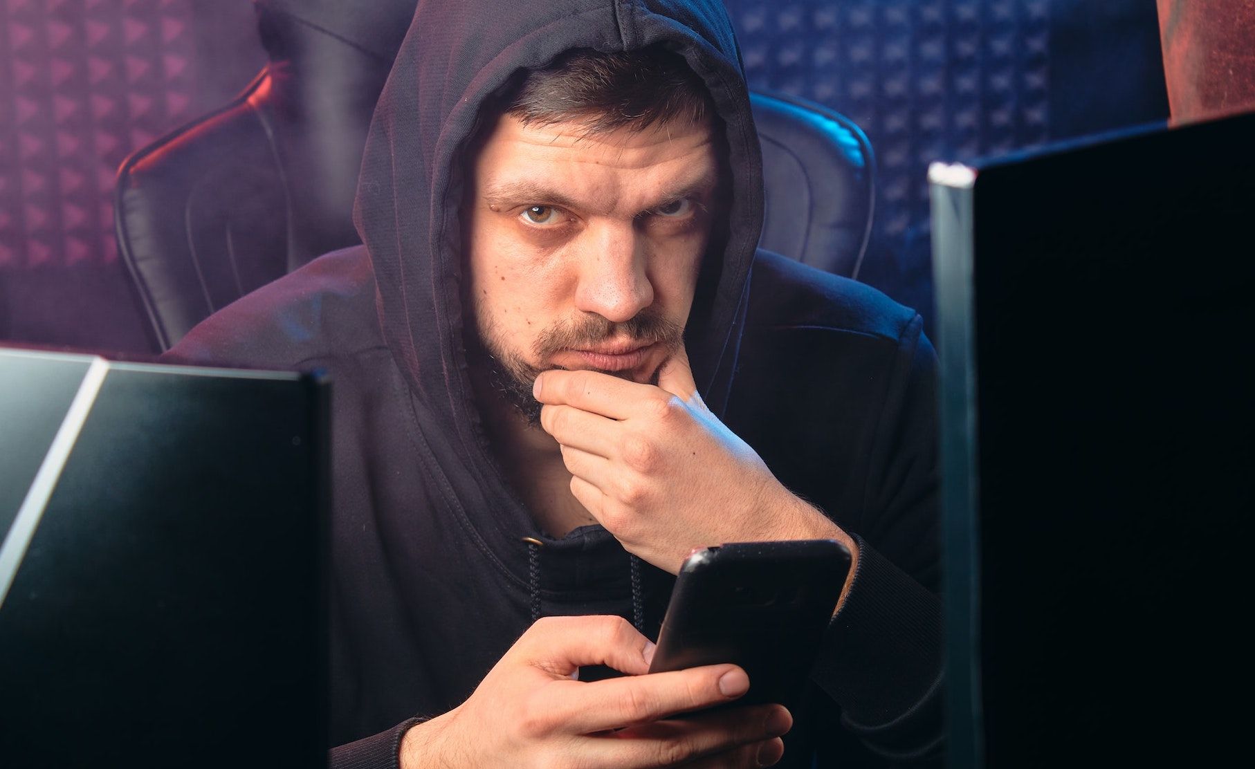 Man wearing a hoodie holding a smartphone 