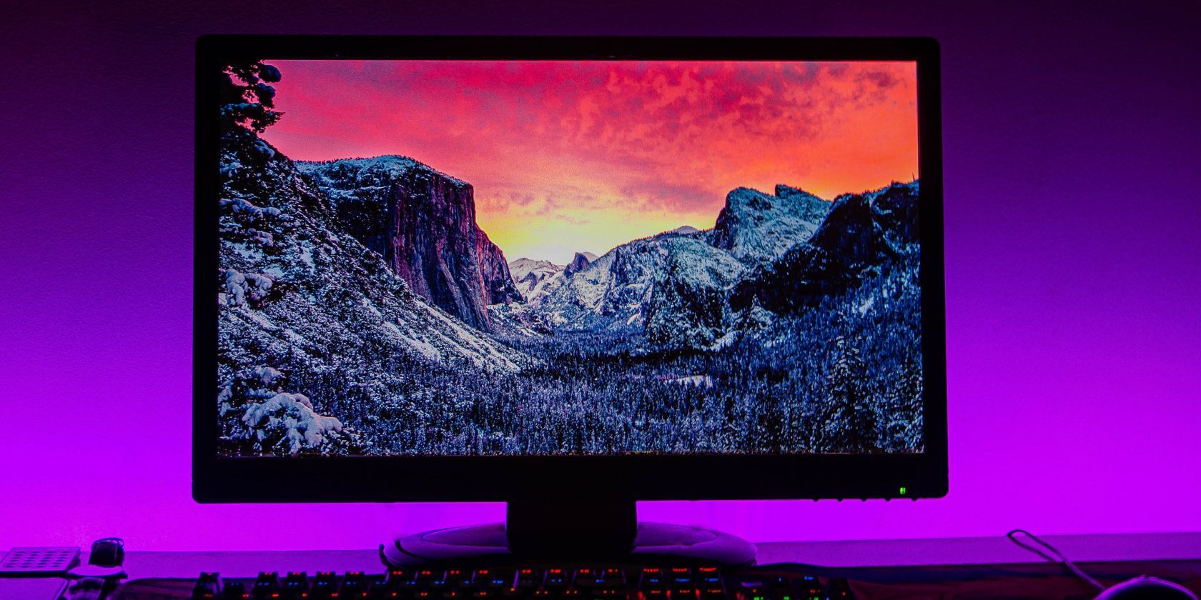 monitor showing desktop background in purple lit room
