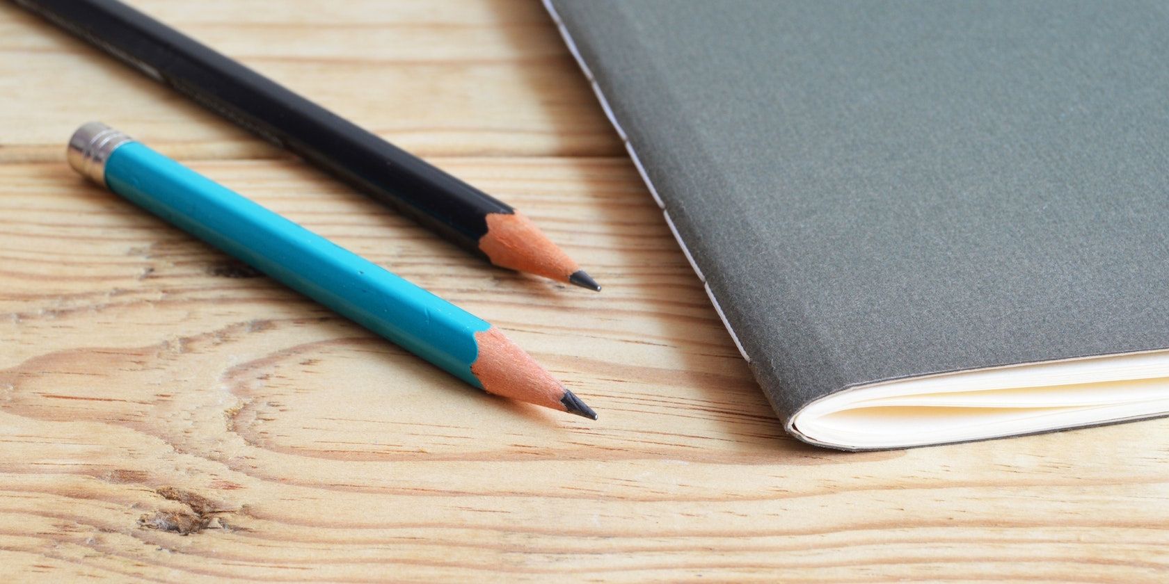 Pencils besides notebook on wooden table