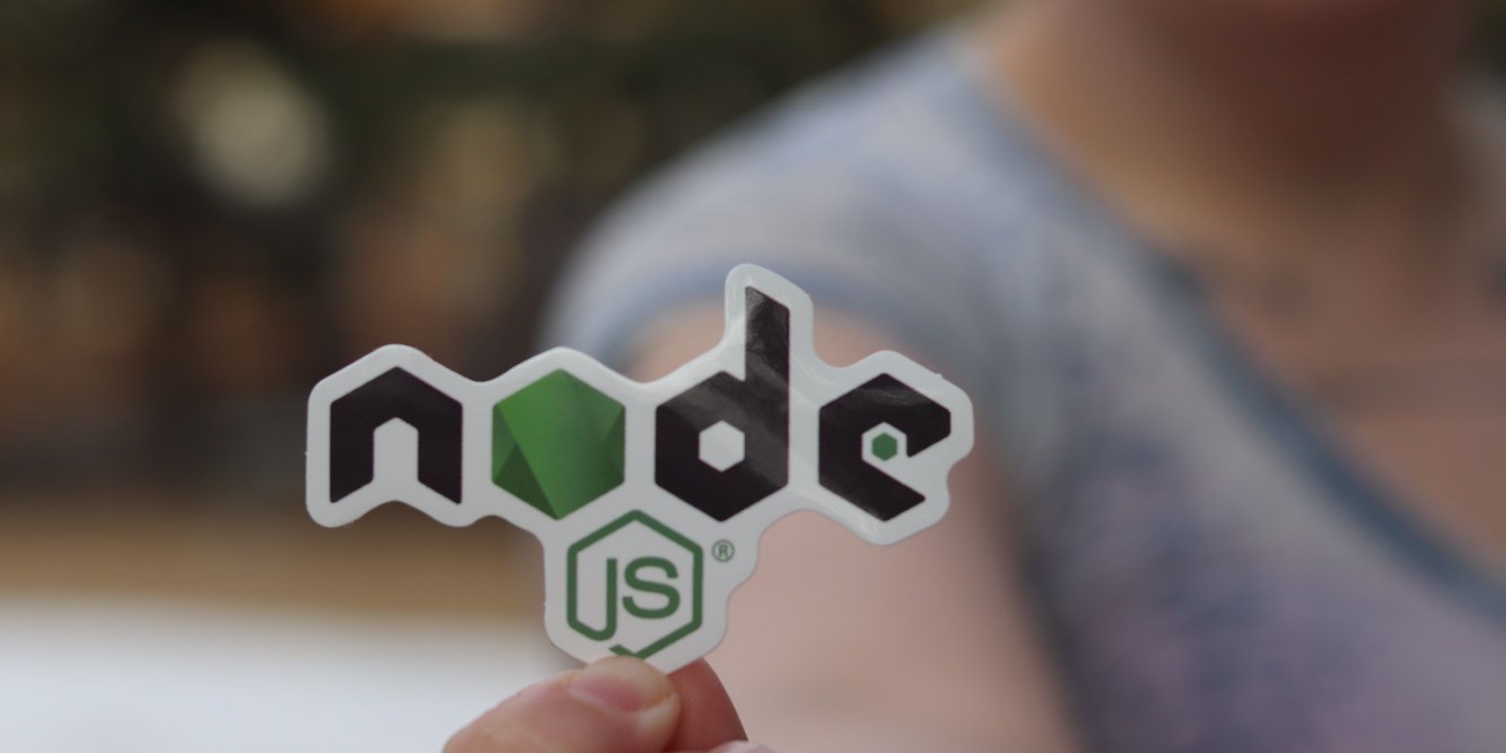 a person holding a Node.js sticker