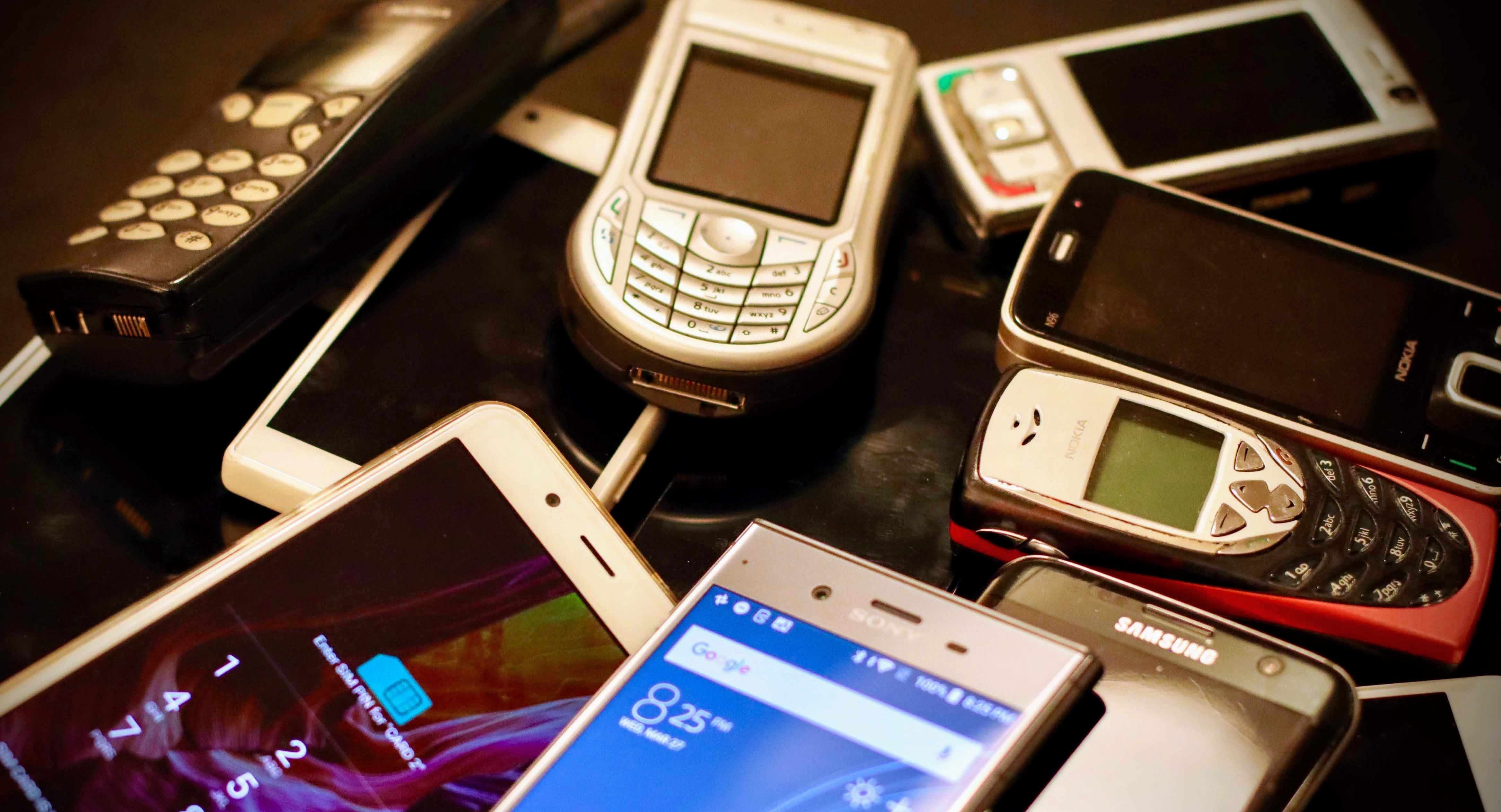 various different cell phones in a pile