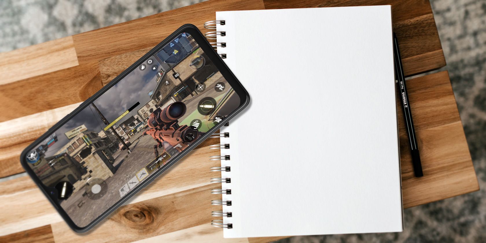 a mobile game on phone screen with notepad aside