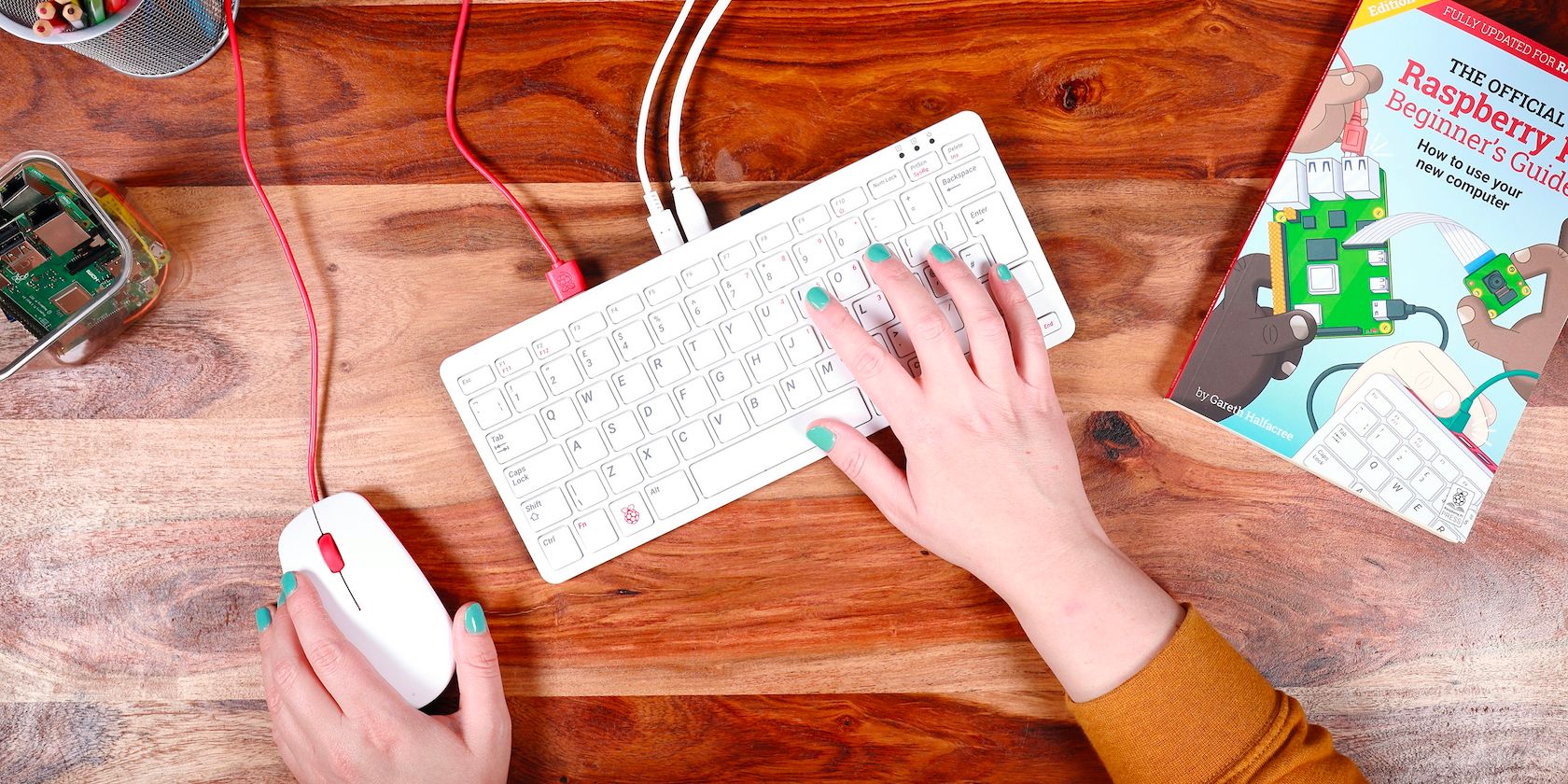 Hand on a mouse and Raspberry Pi 400 keyboard on a desk