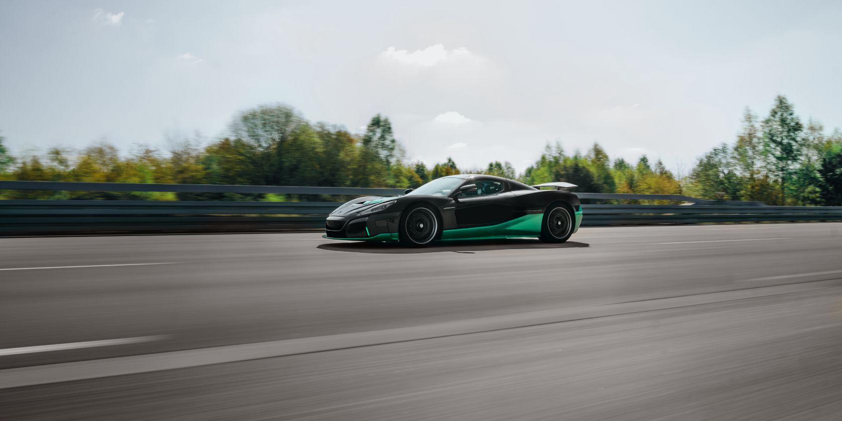 A black and green Rimac Nevera speeding down a track