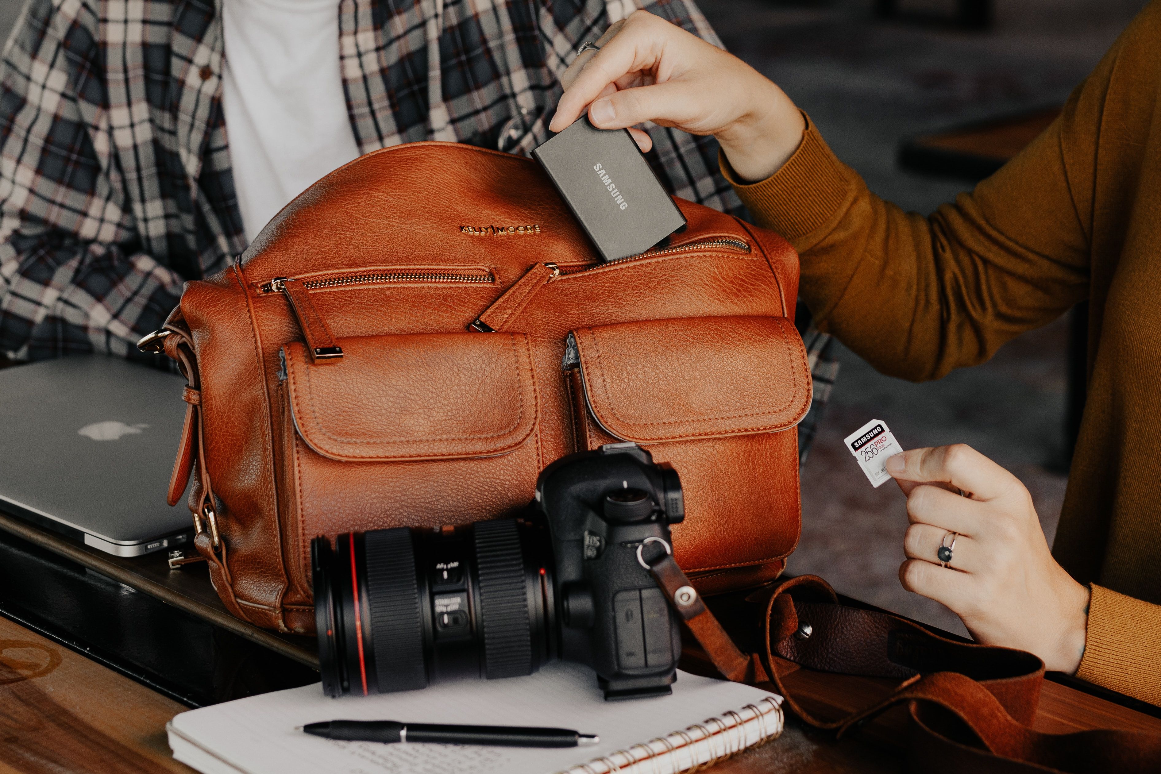 Photo of a person using a bag next to a camera while holding a memory card