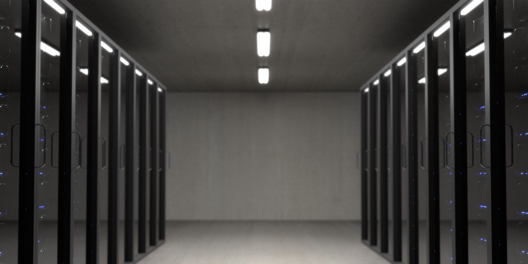 A corridor between rows of server racks behind glass doors.