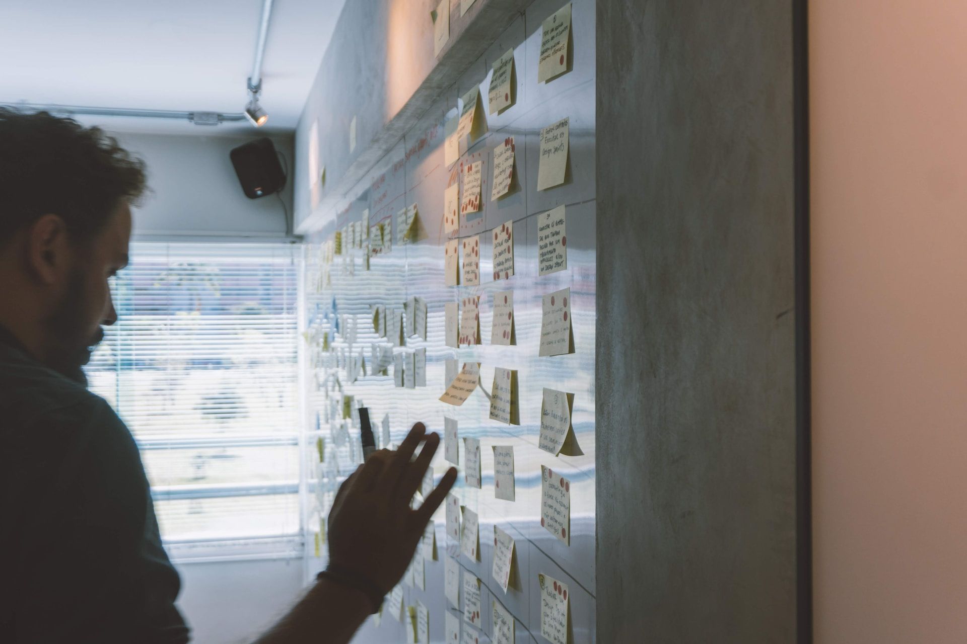 Man looking at a glass wall filled with sticky notes