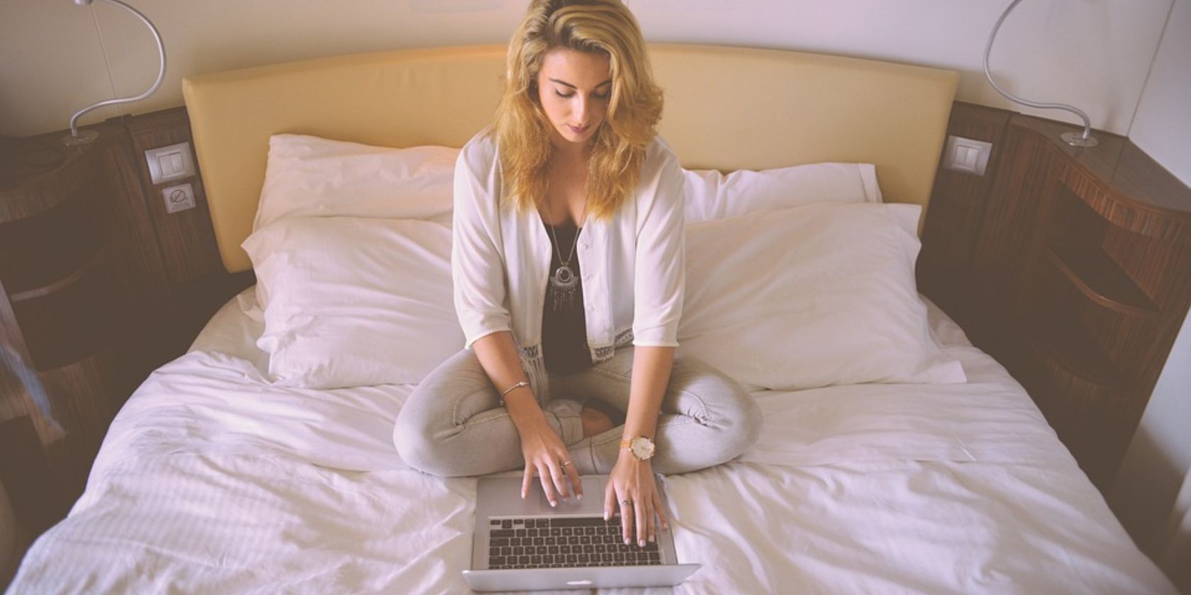 a freelancer woman on a bed using a laptop