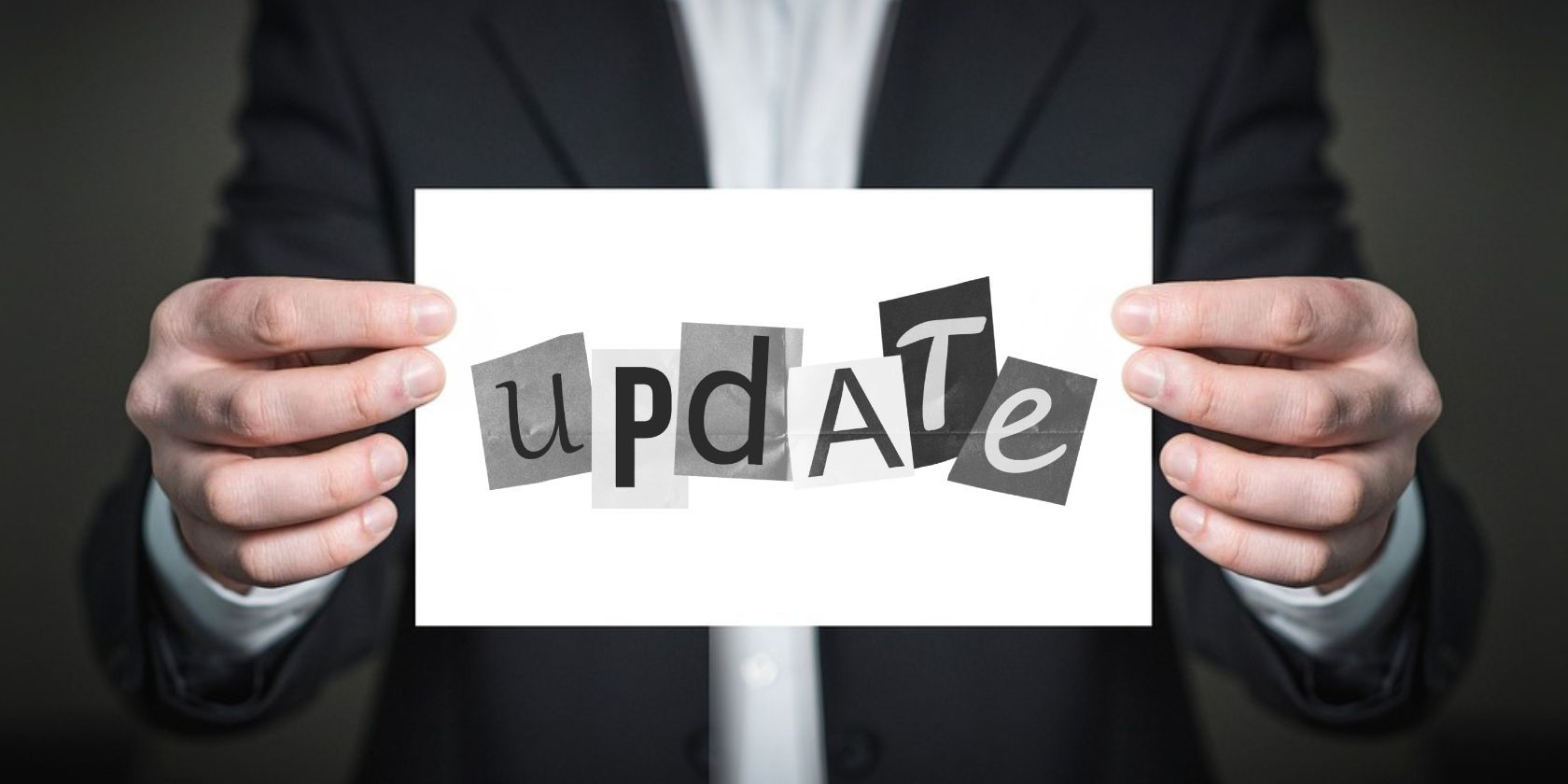 An image of a man holding blank paper with a sticker of the word Update with the letters in different fonts