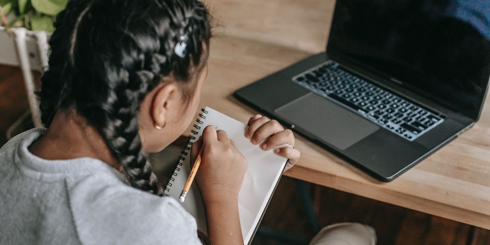 Woman With Braids Writing on Notebook While Using Laptop