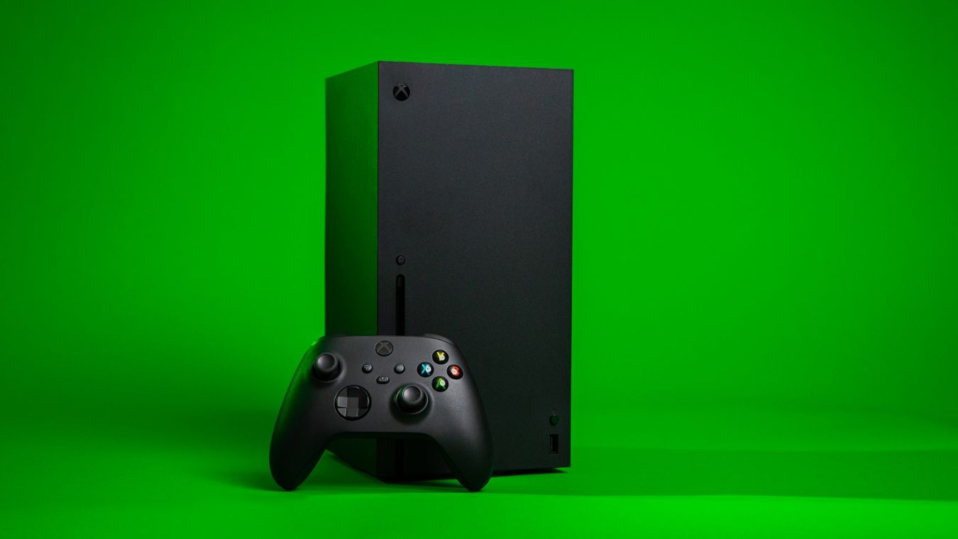 A photograph of an Xbox Series X console with an Xbox Wireless Controller resting in front of the console 