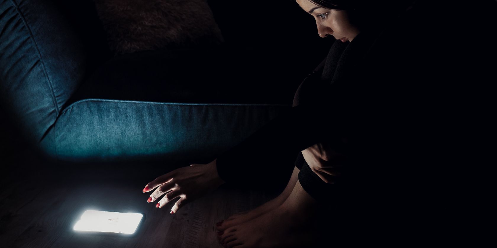 A woman reaching out to her phone while in a dark room