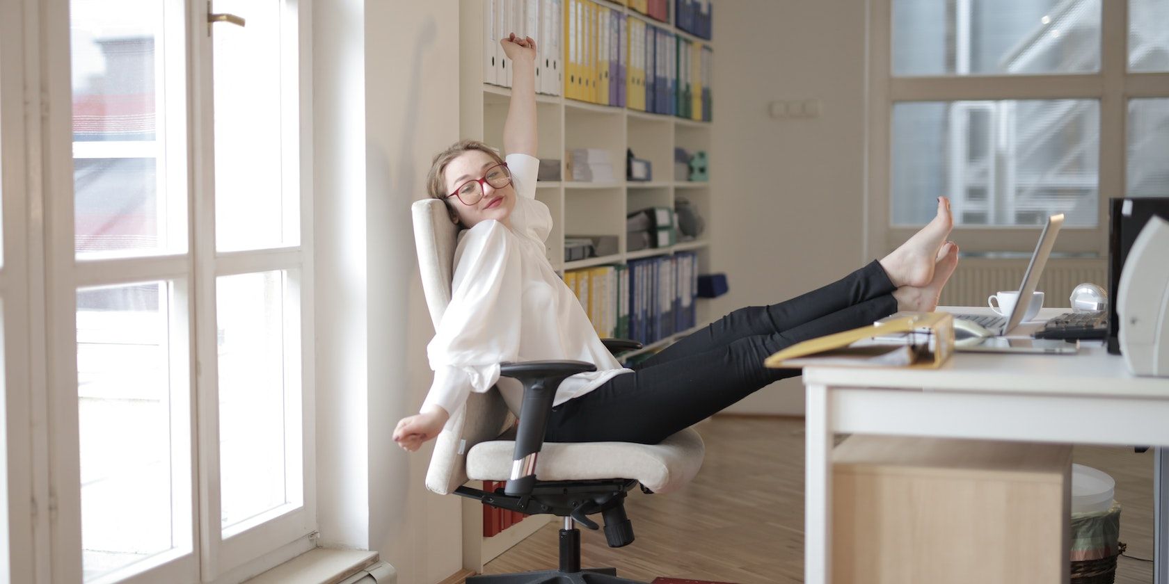 A woman relaxing at her desk with her feet on the table