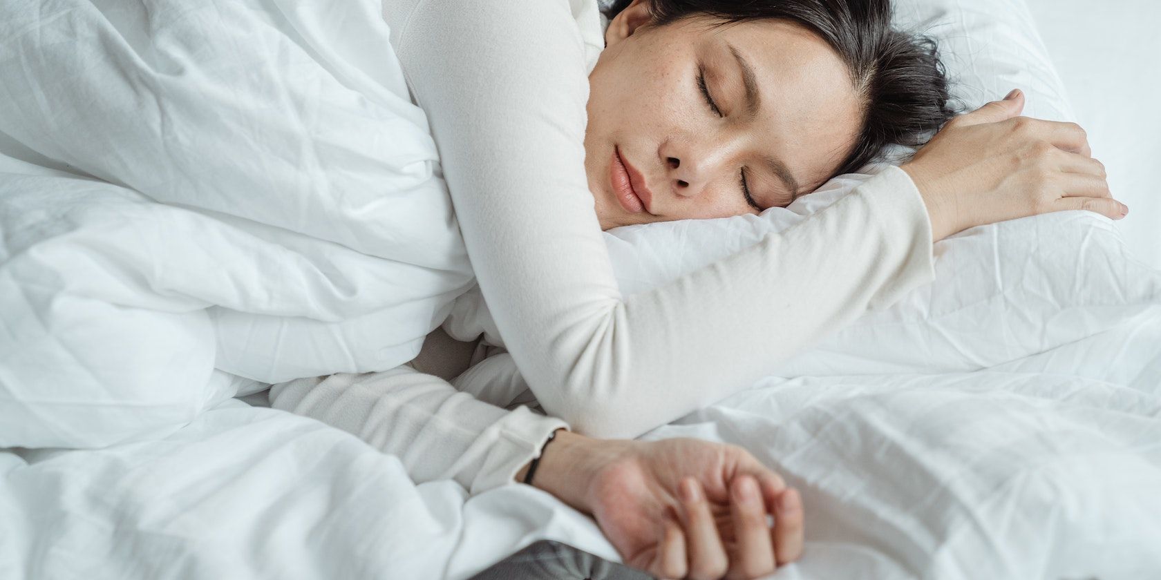 Một người phụ nữ ngủ trên giường gần điện thoại thông minh
