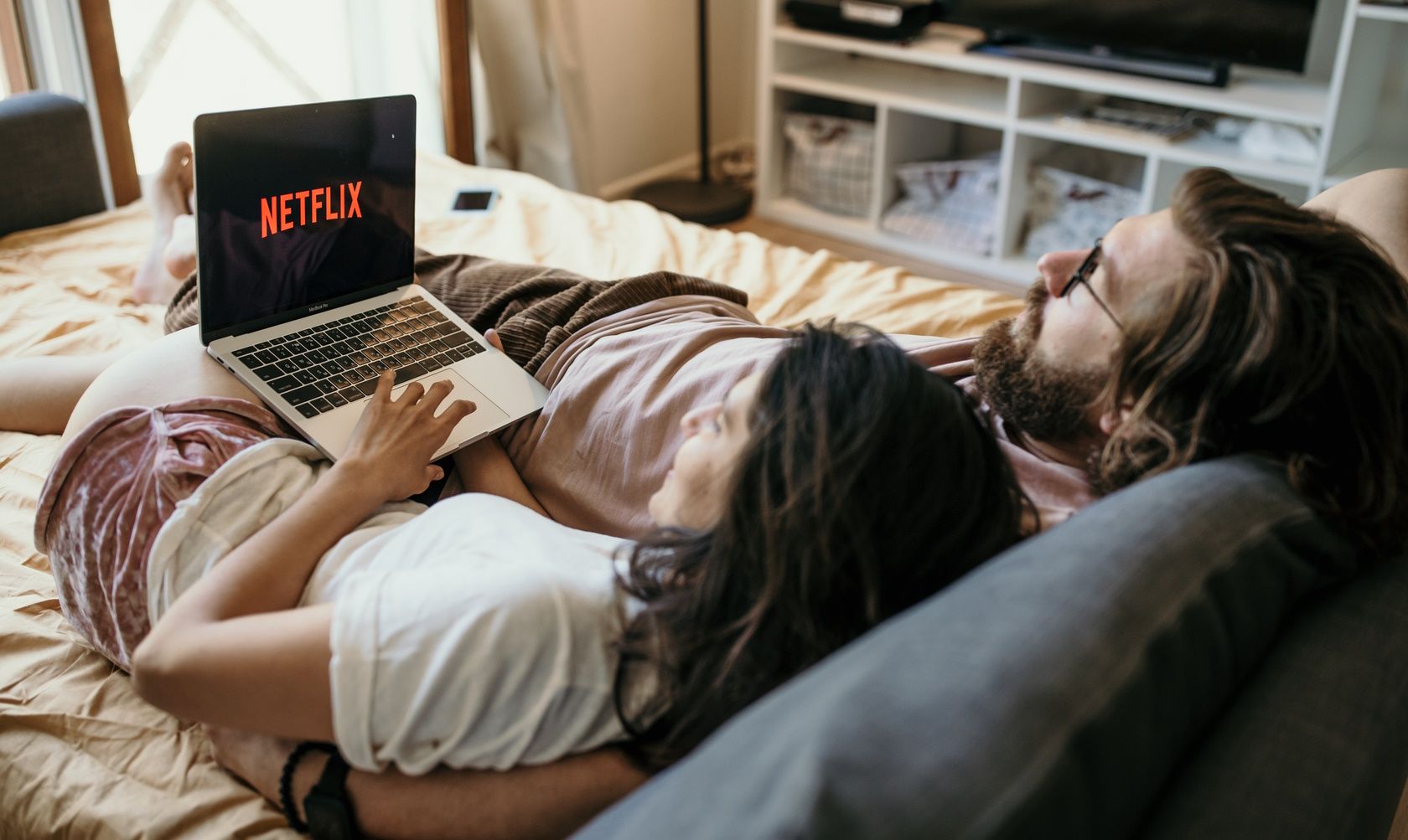 couple lying in bed and watching netflix