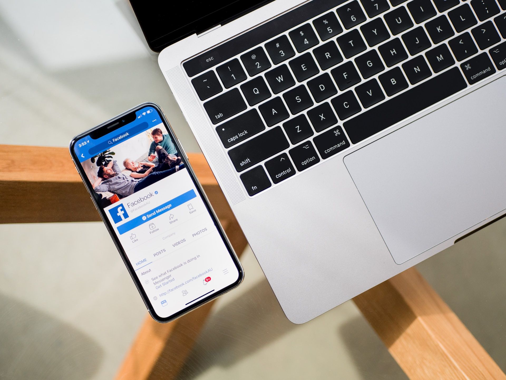 iPhone X displaying the Facebook App beside a MacBook