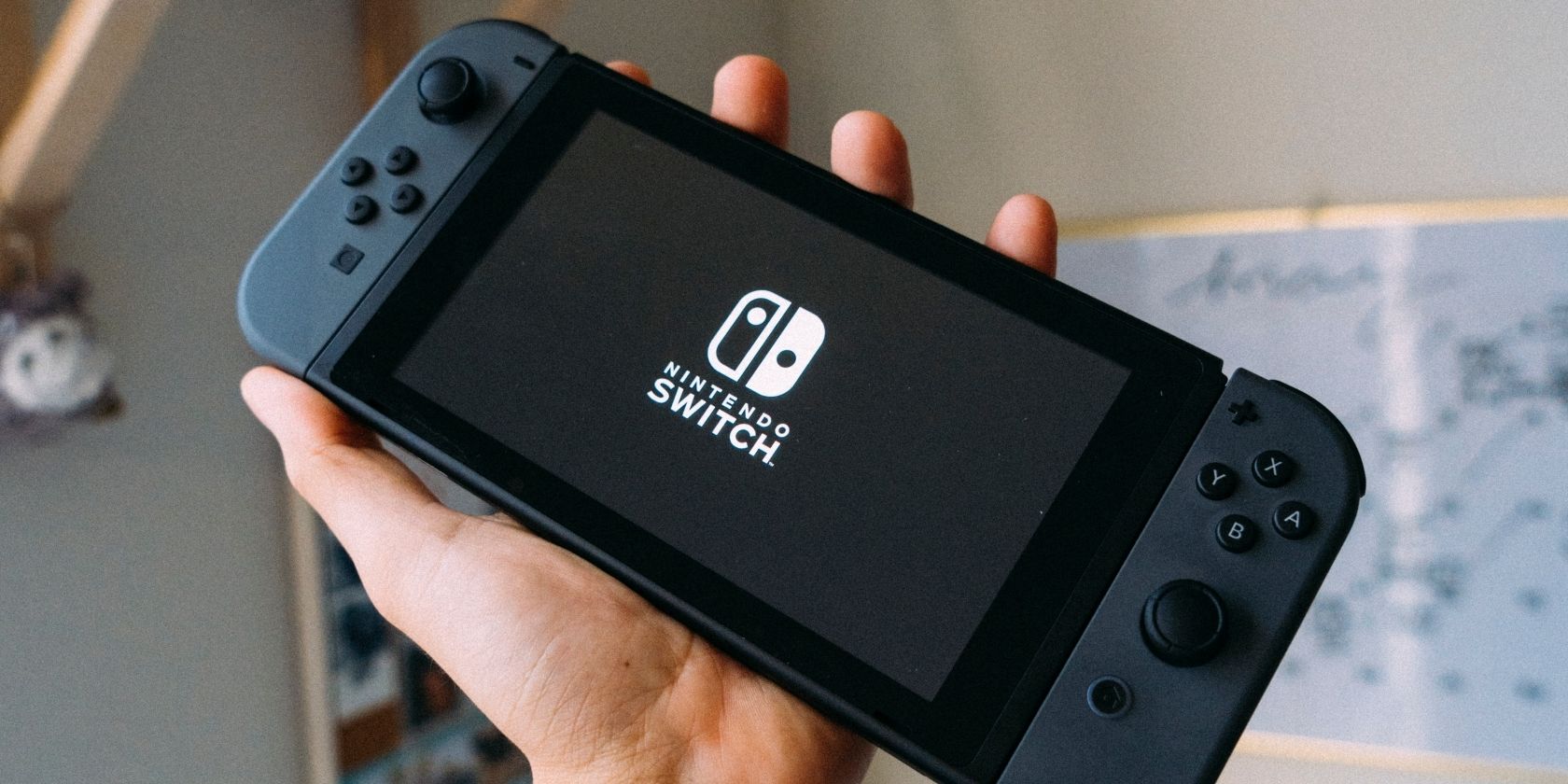 A photograph of a grey Nintendo Switch being held up in the air 
