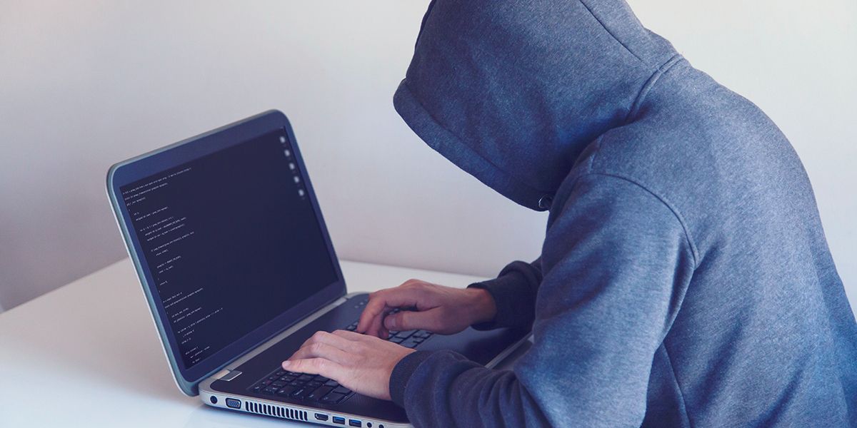 người đàn ông mặc áo hoodie sử dụng máy tính xách tay