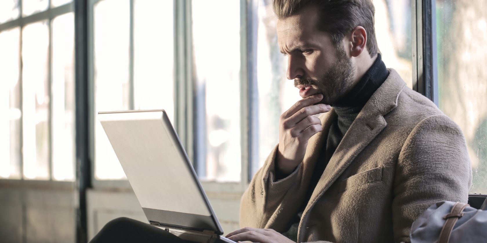 Man holding his chin facing laptop computer