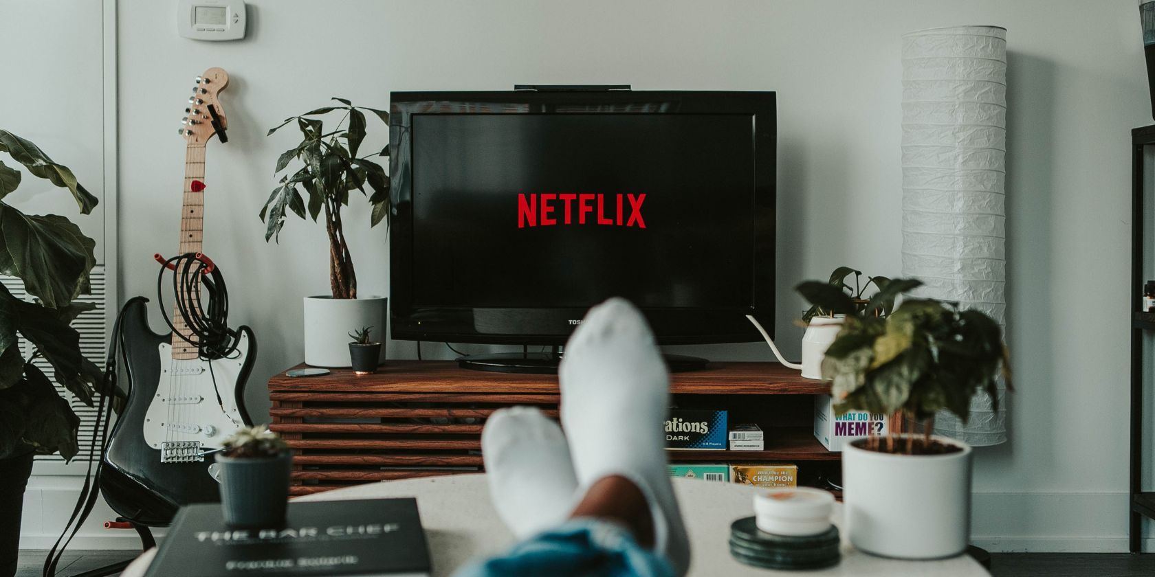A person lounging on the sofa, their feet visible, with Netflix on the TV screen.